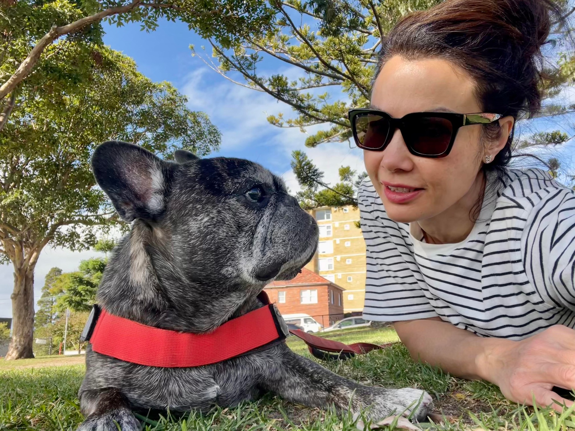 Natalie lying on the grass nose-to-nose with her French Bulldog Duke